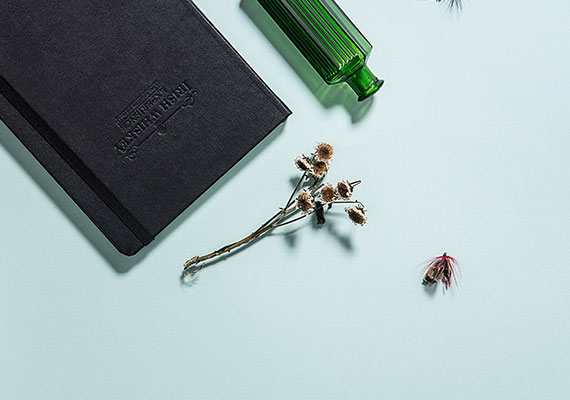 A notebook, pen and bottle on the table.