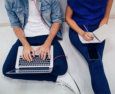 Two people sitting on the ground with laptops