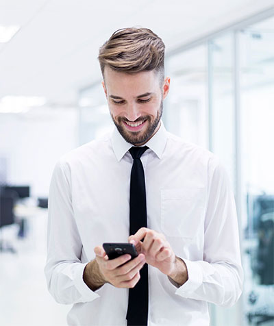 A man in white shirt and tie looking at his phone.