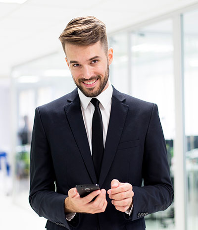 A man in suit and tie holding a cell phone.