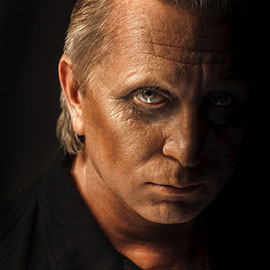 A man with a black shirt and silver hair.