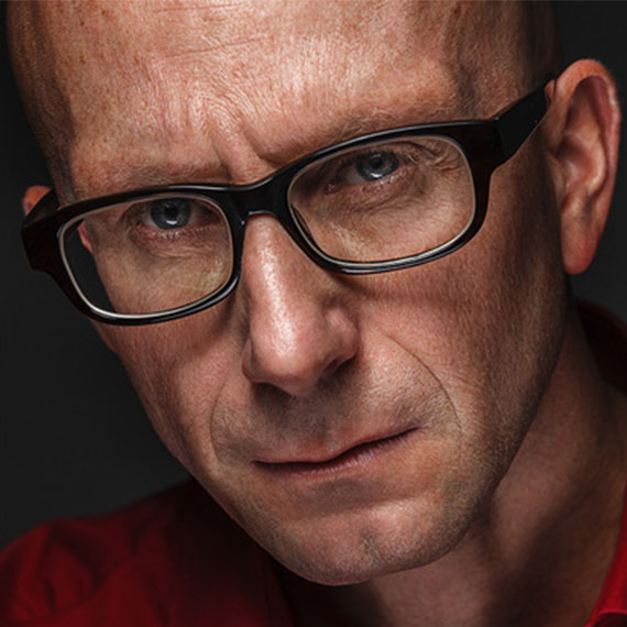 A man with glasses is looking at the camera.