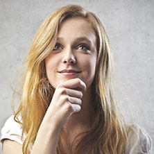 A woman with long hair is smiling and holding her hand to the chin.