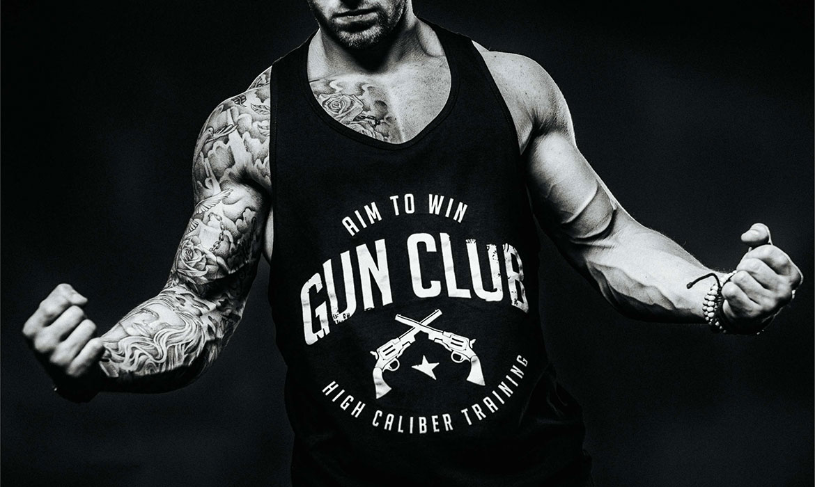 A man with tattoos and a gun club shirt.